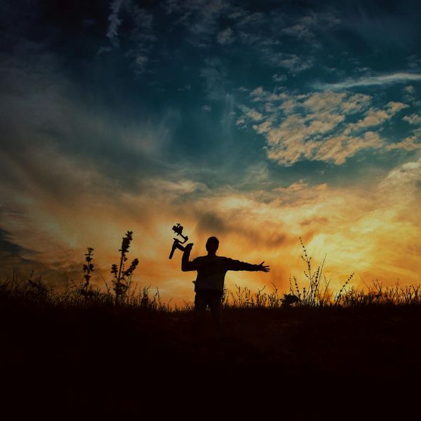 Silhouette of a person meditating at sunset with warm light.